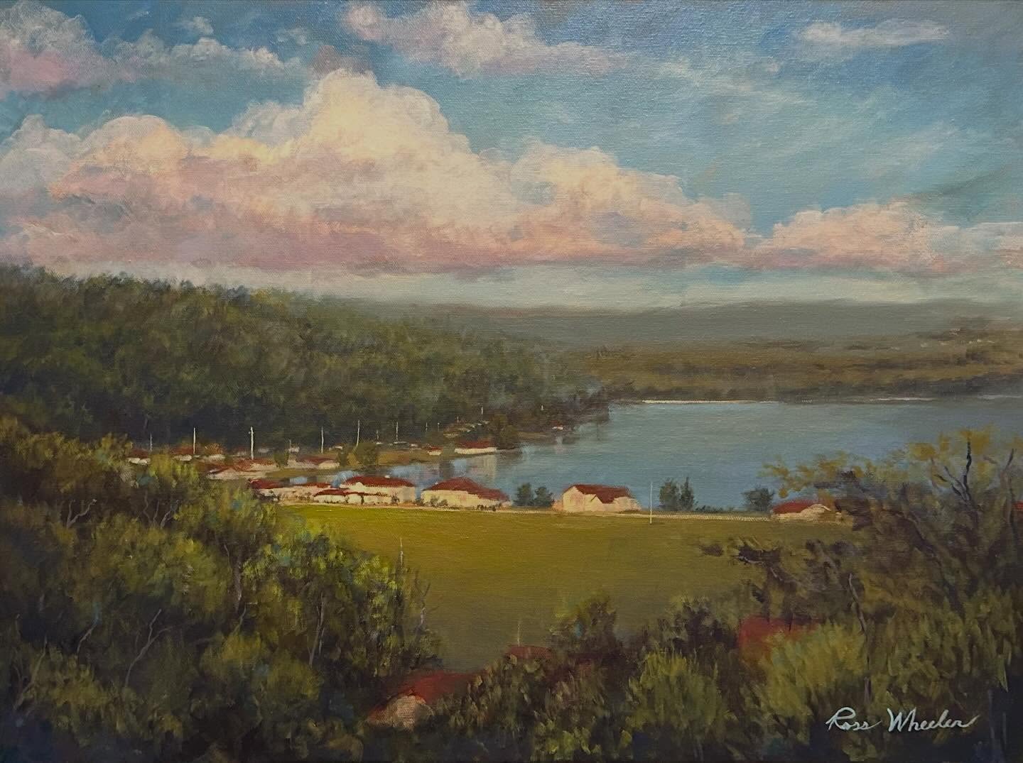 Plein air oil painting of a lake landscape with pink clouds and green hills
